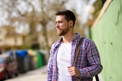 Young man with side bag looking away outdoors