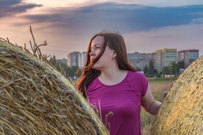 Side view of young woman sitting on hay