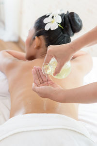 Cropped image of therapist pouring massage oil on woman lying at health spa