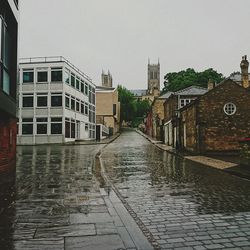 Wet buildings in city against clear sky