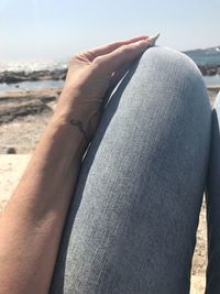 Close-up midsection of woman holing seashell at beach