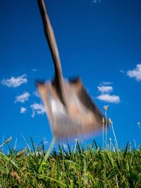 Blurred motion of shovel over field against blue sky