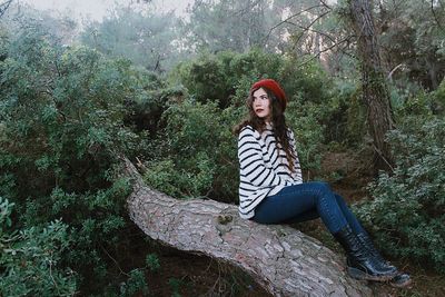 Woman sitting on tree in forest