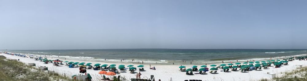 Panoramic view of people at beach against blue sky