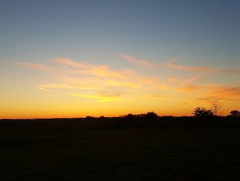 Scenic view of silhouette field against sky at sunset