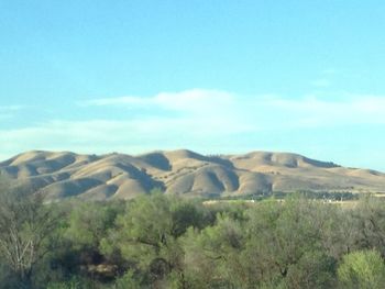 Scenic view of field and mountains against blue sky