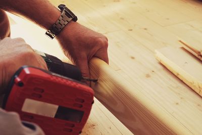 Cropped image of man drilling plank with power tool