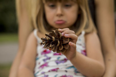 Midsection of mother with daughter holding pine cone