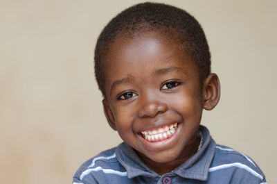 Portrait of cute boy smiling against wall