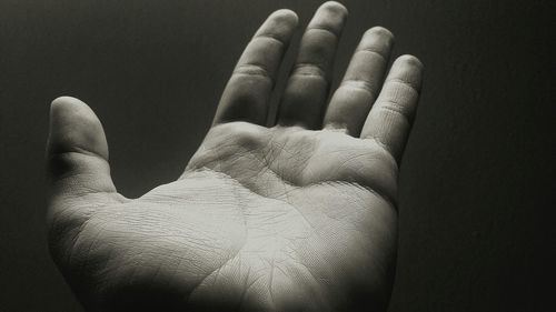 Close-up of wet human hand against black background