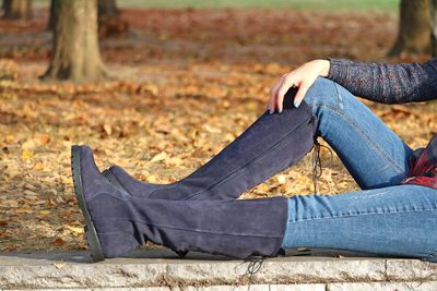 Low section of woman wearing boots sitting in park