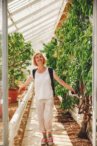 Smiling mid adult woman looking up while standing in greenhouse