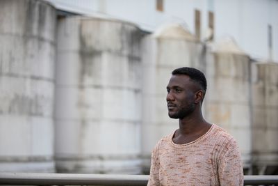 Young man looking away while standing outdoors