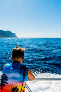 Woman standing in sea against clear blue sky