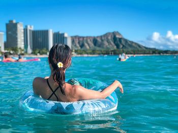 Rear view of woman in swimming pool against sea