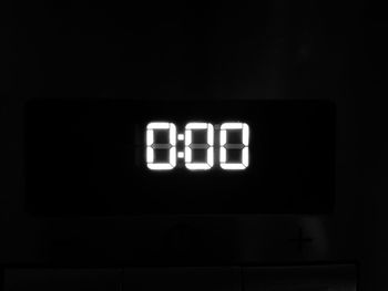 Close-up of illuminated clock in darkroom