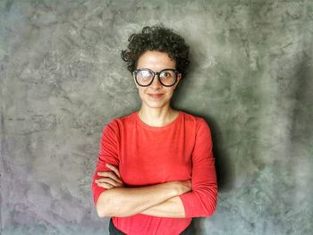 Portrait of smiling woman standing against wall