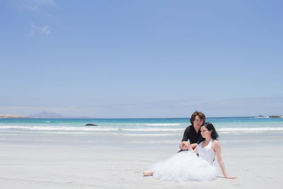 Friends on beach against clear sky