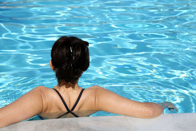 High angle view of woman relaxing in swimming pool on sunny day