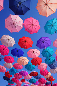 Low angle view of colorful umbrellas against clear blue sky