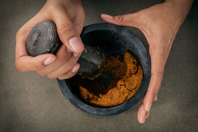 Cropped hands of person preparing food in mortar and pestle