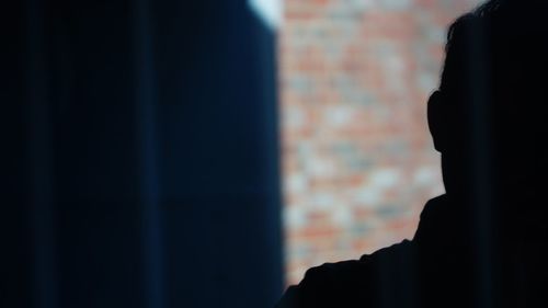 Close-up portrait of silhouette man standing against wall