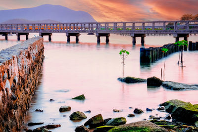 Bridge over river against sky during sunset