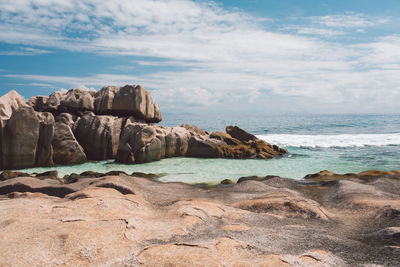 Rock formation on beach against sky