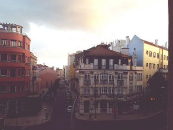 Cars on street amidst buildings against sky during sunset