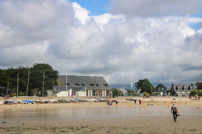 People on beach by buildings against sky