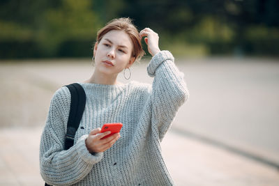 Young woman looking away while standing outdoors