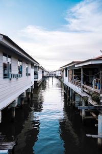 Pier over canal amidst buildings against sky