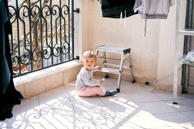 Cute boy sitting on tiled floor