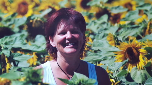 Portrait of happy woman amidst sunflowers