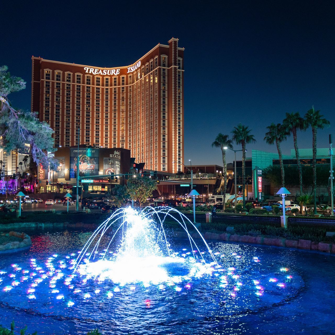 ILLUMINATED FOUNTAIN BY BUILDING AGAINST SKY AT NIGHT