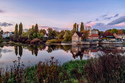 Scenic view of lake by buildings against sky at sunset in celle, germany.