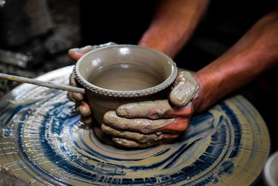 Cropped hand making clay pot