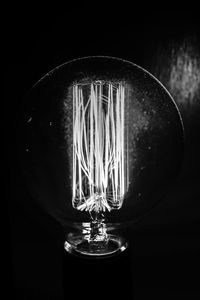 Close-up of illuminated light bulb against black background