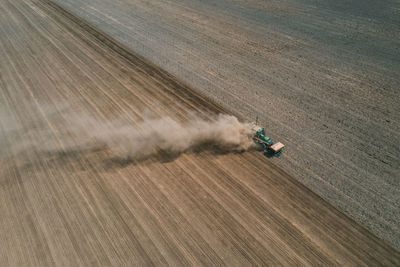 Aerial view the tractor is working in the field creating dust clouds. spring work in the field. 