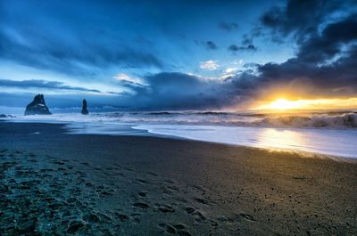 Scenic view of beach against dramatic sky