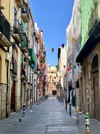 Colorful flags and posts decorate a narrow alley in tarragona, spain.