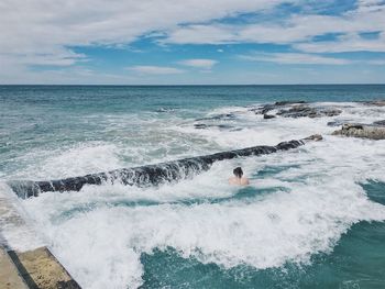 Man swimming in infinity pool by sea against sky