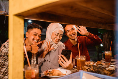 Cheerful friends eating food at stall