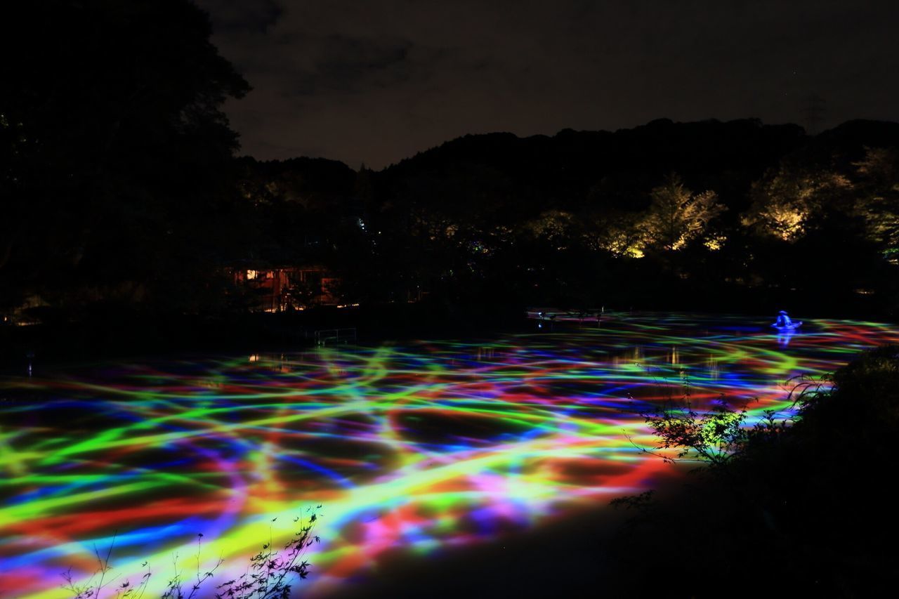 MULTI COLORED LIGHT TRAILS IN SKY AT NIGHT