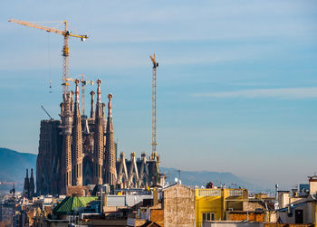 Cranes at construction site against sky in city