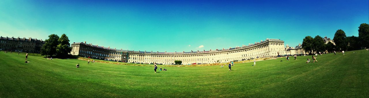 architecture, grass, clear sky, built structure, building exterior, large group of people, copy space, blue, famous place, tourism, travel destinations, green color, tourist, history, travel, lawn, person, tree, leisure activity