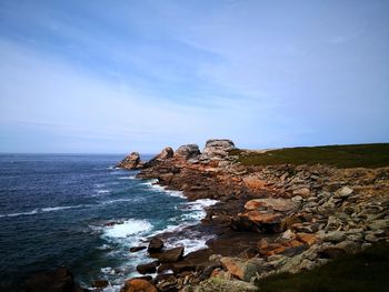 Rocks on sea shore against sky