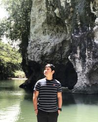 Young man looking away while standing on rock