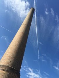 Low angle view of chimney against contrail at blue sky