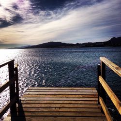 Wooden pier on lake against cloudy sky